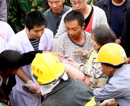 5月13日,救護(hù)人員把被救出的學(xué)生抬往醫(yī)院。 四川綿竹市漢旺鎮(zhèn)武都小學(xué)的教學(xué)樓在地震中倒塌,眾多師生被埋在倒塌的校舍中。救援行動(dòng)正在積極展開(kāi)。 新華社記者 陳建力 攝