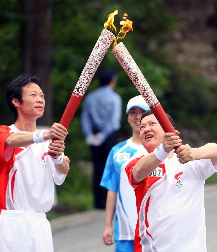 5月15日,奧運(yùn)火炬手熊友春(右)與蔡德忠在傳遞過程中交接。當(dāng)日,北京奧運(yùn)會圣火傳遞活動在江西井岡山舉行。 新華社記者 邢廣利 攝