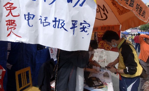 5月15日上午,災(zāi)民在綿陽市區(qū)通過免費(fèi)電話與親人聯(lián)系。 目前,中國移動公司已經(jīng)在四川省境內(nèi)設(shè)立了2100多個移動通信救災(zāi)及便民服務(wù)點(diǎn),為受災(zāi)群眾提供免費(fèi)應(yīng)急通話、長途電話“報(bào)平安”、手機(jī)充電等服務(wù)。 新華社記者 趙穎全 攝
