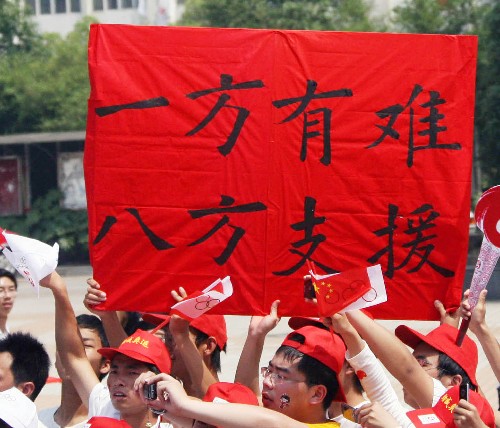 5月16日,當?shù)厝罕娫谟^看圣火傳遞時打出標語支持災區(qū)。當日,北京奧運圣火傳遞活動在江西南昌舉行。 新華社記者 李穎 攝