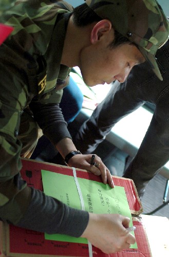 5月16日,解放軍某紅軍師副政委劉渠在空投前將鼓勵群眾的話寫在宣傳單上。 當日,解放軍某紅軍師官兵準備借助直升機從四川綿竹市金花鎮(zhèn)的深山中轉(zhuǎn)移受傷災(zāi)民,但因不具備降落條件,只好先為災(zāi)民空投藥品、食物和礦泉水等物資。 新華社記者 苑堅 攝