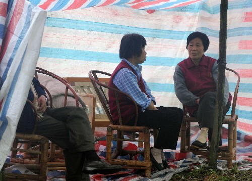 5月13日,都江堰聚源鎮(zhèn)的幾名災(zāi)民在自己搭建的帳篷中聊天。盡管汶川地震給四川當?shù)鼐用竦纳钤斐珊艽笃茐模S多人被迫居住在條件簡陋的臨時居所中,但生活依舊在繼續(xù)。 新華社記者 王建華 攝