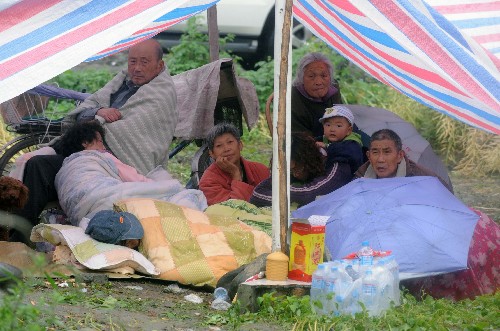 5月13日,都江堰聚源鎮(zhèn)的幾名災(zāi)民聚集在自己搭建的帳篷中。盡管汶川地震給四川當?shù)鼐用竦纳钤斐珊艽笃茐?,許多人被迫居住在條件簡陋的臨時居所中,但生活依舊在繼續(xù)。 新華社記者 王建華 攝