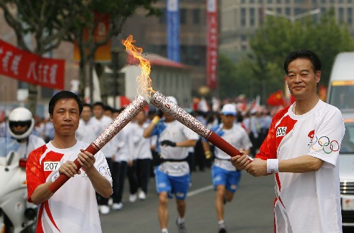 5月23日,火炬手沈富麟(右)與火炬手周建明交接。當(dāng)日,北京奧運(yùn)會(huì)圣火在上海傳遞。 新華社記者 凡軍 攝