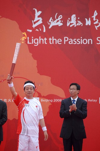 5月26日,第一棒火炬手張云泉(左)在起跑儀式上展示火炬。當日,北京奧運會圣火在江蘇泰州傳遞。 新華社記者 韓瑜慶 攝