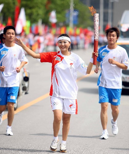 5月28日,奧運(yùn)火炬手朱玲敏手持火炬?zhèn)鬟f。當(dāng)日,北京奧運(yùn)會(huì)圣火在安徽合肥傳遞。 新華社記者 邢廣利 攝