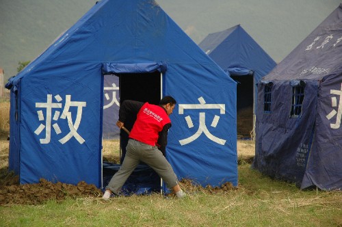 這是5月20日,自愿自費(fèi)到地震災(zāi)區(qū)參加抗震救災(zāi)的唐山農(nóng)民宋志永在安縣曉壩鎮(zhèn)受災(zāi)群眾安置點(diǎn)的帳篷邊挖掘排水溝。 新華社記者 張米揚(yáng) 攝