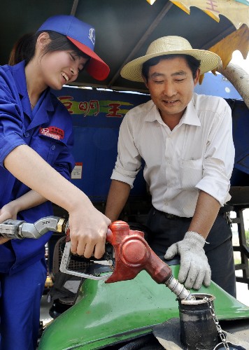 6月5日,山東省棗莊市一家石油公司的工作人員在該市桑村鎮(zhèn)田間為收割機加油。 新華社發(fā)(李宗憲 攝)