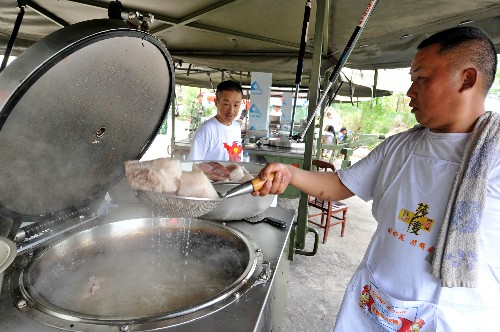 6月5日,在四川省彭州市龍門山鎮(zhèn)九峰村受災(zāi)群眾的帳篷里,由當(dāng)?shù)孛癖M成的炊事班成員正在為群眾準(zhǔn)備飯菜。 新華社記者 張國俊 攝