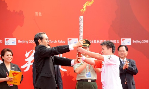 6月6日,廣西壯族自治區(qū)主席馬飚(前左)將火炬交給第一棒火炬手唐靈生。當(dāng)日,北京奧運圣火在廣西桂林傳遞。 新華社記者 安治平 攝