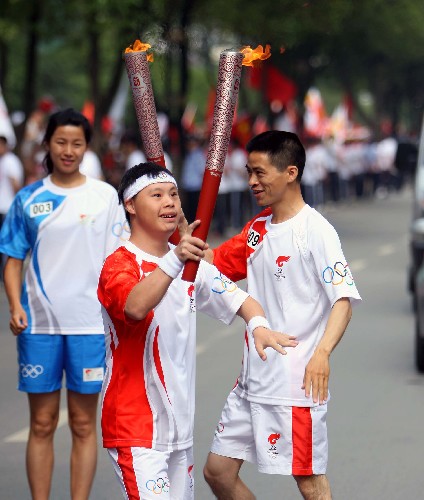 6月6日,火炬手石樂(中)與上一棒火炬手陳君龍交接后開始傳遞。當(dāng)日,北京奧運(yùn)圣火在廣西桂林傳遞。 新華社記者 邢廣利 攝