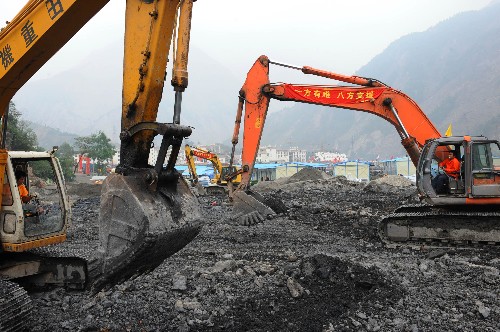 6月17日,施工人員利用大型機(jī)械在四川省汶川縣映秀鎮(zhèn)地震廢墟前加緊平整土地。 新華社記者 張國(guó)俊 攝