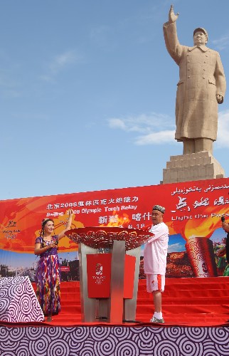 6月18日,火炬手達(dá)吾提·阿西木(右)點燃圣火盆。當(dāng)日,北京奧運圣火在新疆喀什傳遞。 新華社記者 邢廣利 攝