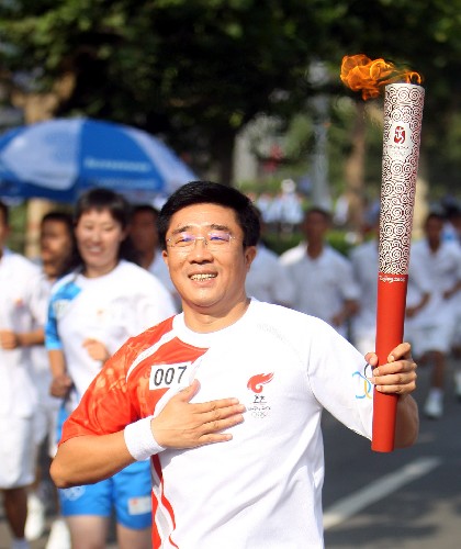6月25日,奧運(yùn)火炬手陳利民手持火炬?zhèn)鬟f。當(dāng)日,北京奧運(yùn)圣火在山西運(yùn)城傳遞。 新華社記者 邢廣利 攝