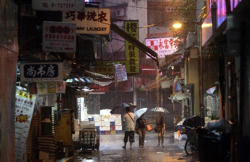 6月25日,人們冒雨行走在香港的小巷中。 新華社記者 周磊 攝
