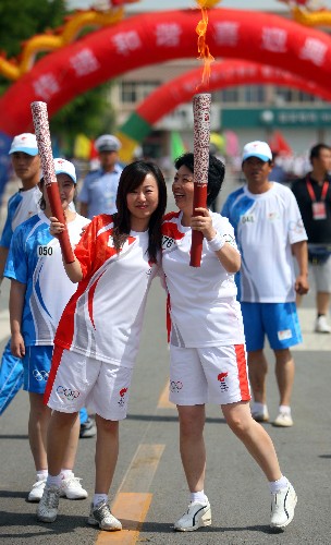 6月30日,火炬手譚興玲(右)與下一棒火炬手駱佳交接。當日,北京奧運圣火在寧夏吳忠傳遞。 新華社記者 邢廣利 攝