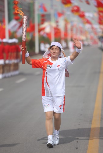 6月30日,火炬手馬曉梅手持火炬?zhèn)鬟f。當日,北京奧運圣火在寧夏吳忠傳遞。 新華社記者 邢廣利 攝
