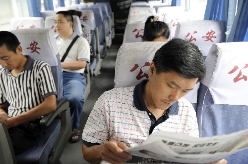7月3日,考生家長在考點外、哈爾濱特警提供的空調(diào)大巴上休息。 新華社記者 戴旭明 攝