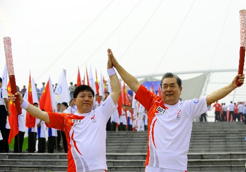 7月17日,第一棒火炬手、中國(guó)奧運(yùn)第一人劉長(zhǎng)春之子劉鴻圖(右)與下一棒火炬手許福軍進(jìn)行交接。當(dāng)日,北京奧運(yùn)圣火在沈陽(yáng)市傳遞。 新華社記者 任勇 攝