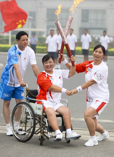 7月28日,火炬手張峻英(右)與下一棒火炬手賈紅交接。當(dāng)日,北京奧運(yùn)圣火在河南省安陽(yáng)市傳遞。 新華社記者 邢廣利 攝