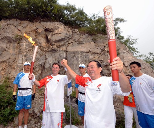 8月8日,火炬手田雄(右二)與下一棒火炬手施泰納交接后握手致意。當(dāng)日,北京奧運(yùn)圣火在北京市傳遞。 新華社記者 邢廣利 攝