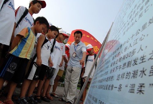 8月18日,一名志愿者在錢(qián)塘江邊向孩子們宣講潮水的危險(xiǎn)。 新華社記者 黃深鋼 攝