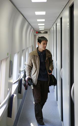12月16日,一名記者正經(jīng)過列車的車廂走道。 新華社記者 裴鑫 攝