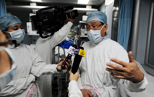 8月13日,廣東省甲型H1N1流感臨床救治專(zhuān)家組副組長(zhǎng)肖正倫教授(右)在向記者介紹患者情況。新華社記者 陳曄華 攝