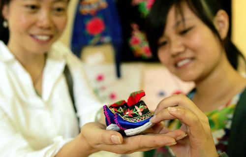 8月14日,參觀者被一雙小巧的彝族刺繡工藝品鞋吸引。新華社記者 施思思攝