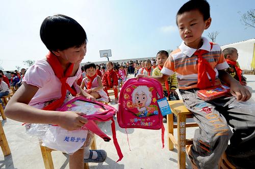 8月31日,兩名小學(xué)生在開學(xué)典禮上欣賞剛領(lǐng)到的新書包。新華社記者 朱祥 攝