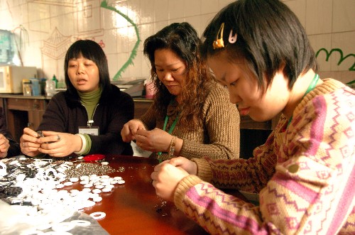 12月3日,一位智障人士(右一)和家長(zhǎng)一起在廣州德福之家加工出口的手工藝品。 新華社記者 壯錦 攝