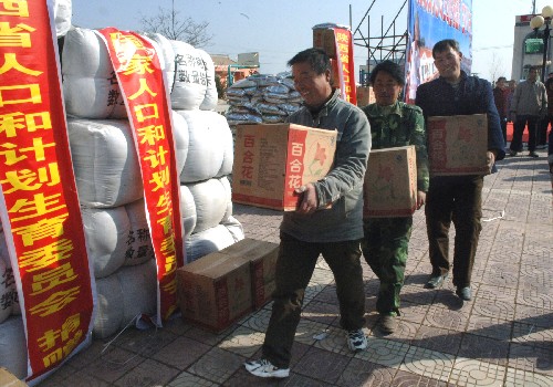 1月9日,旬邑縣職田鎮(zhèn)車村的幾位農(nóng)民領(lǐng)取國家人口和計劃生育委員會捐贈的食品。 新華社記者 何俊昌 攝