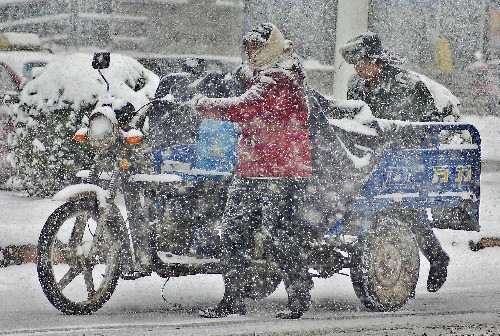 1月26日,市民冒雪推車(chē)走在巢湖市長(zhǎng)江路上。 新華社發(fā)