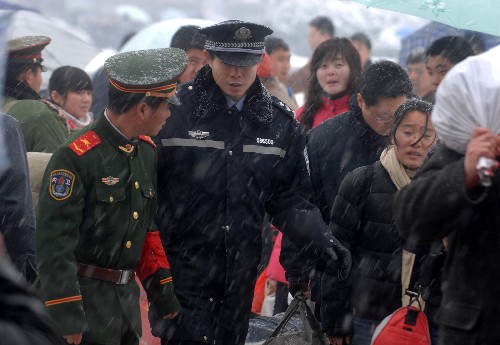1月27日,在合肥火車站的執(zhí)勤人員冒雪維持秩序,引導(dǎo)旅客上車。 新華社記者 王雷 攝