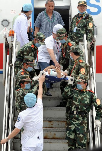 5月23日,武警戰(zhàn)士和醫(yī)務(wù)人員一起將傷員抬下飛機。 新華社記者 孫參 攝