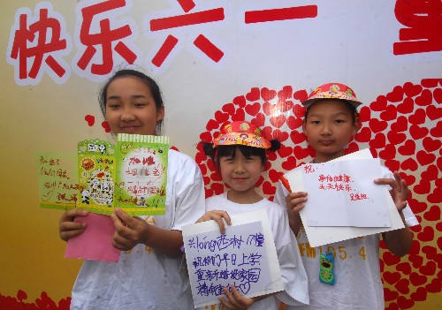 6月1日,來自四川廣元的13歲女孩張瑞(左一)與杭州孩子們一起展示寫好的賀卡,準備寄給四川災區(qū)的孩子們。 當日,十多名來自四川災區(qū)的孩子們與杭州孩子們一起,唱歌、做游戲、結對子,度過一個特別的兒童節(jié)。 新華社記者 徐昱 攝