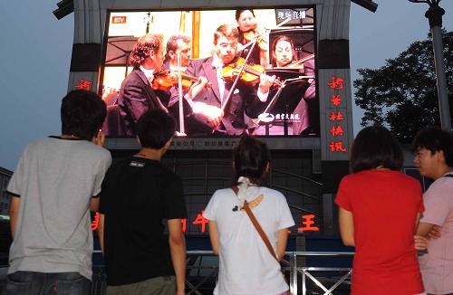 7月4日,市民在北京火車站前的戶外電子大屏幕前駐足欣賞國(guó)家大劇院“漫步經(jīng)典系列音樂(lè)會(huì)”的現(xiàn)場(chǎng)直播。 新華社記者 羅曉光 攝