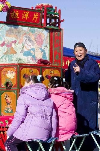 1月24日,在北京國(guó)際雕塑公園的文化廟會(huì)上,一名拉洋片藝人為孩子們表演。當(dāng)日,北京國(guó)際雕塑公園舉辦2009年新春文化廟會(huì),各類商品和富有特色的表演吸引了眾多市民前來(lái)參與。