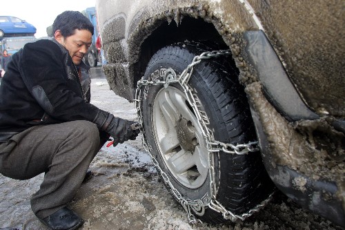 1月22日,司機(jī)給車輛安裝防滑鏈。因大雪天氣而通行受阻的西漢高速公路于當(dāng)日恢復(fù)通車。由于秦嶺澇峪口至朱雀森林公園20多公里路段嚴(yán)重結(jié)冰,執(zhí)勤交警和路政人員要求司機(jī)在這一路段必須安裝防滑鏈,慢速通行,交警每20分鐘放行一批車輛,以保證西漢高速秦嶺路段暢通。 新華社發(fā)(袁景智 攝)