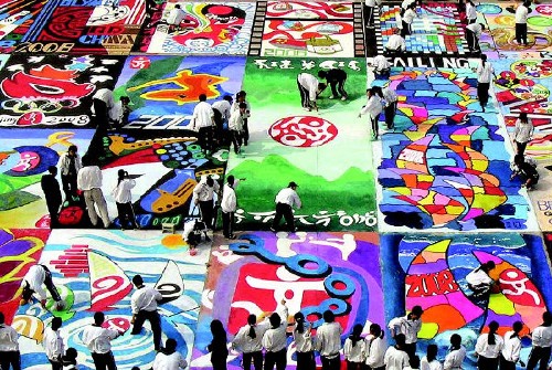 北京2008年奧運會在人們熱切的期盼中一步步走近,不熄的奧運圣火點燃了中國人民奔放四溢的激情,人們以各自不同的方式迎接奧運會的到來:巨龍勁舞、千帆競渡、大地彩畫、沙雕群像、百人靜漂、眾人博弈、揮拳太極、輪滑競賽……一幅幅異彩紛呈的畫面,展示了悠久厚重的中華民族文化和中國人特有的聰明才智;一個個多姿多彩的場景,凝聚了無數(shù)中國人對奧運的憧憬和熱情。 2004年10月20日,青島市第六中學1300余名學生在面積800平方米的巨幅“畫布”上描繪心目中的2008年北京奧運會。 新華社發(fā)