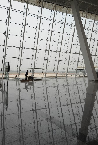 這是一名工人在新建成的武漢天河機(jī)場第二航站樓候機(jī)大廳里清掃地面(3月25日拍攝)。新華社記者 程敏 攝