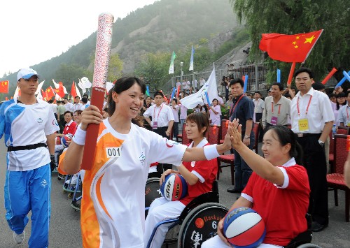 9月4日,第一棒火炬手朱宏艷(左二)與前來(lái)加油助威的輪椅籃球運(yùn)動(dòng)員擊掌相慶。當(dāng)日,北京殘奧會(huì)圣火在河南洛陽(yáng)進(jìn)行傳遞。 新華社記者 金良快 攝