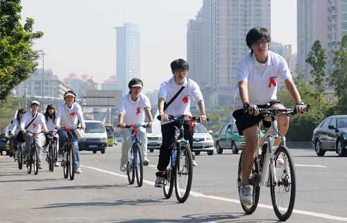 12月1日,暨南大學(xué)學(xué)生胸戴“紅絲帶”在廣州街頭參加騎車?yán)@城宣傳活動。當(dāng)日是世界艾滋病日,各地舉行防治艾滋病宣傳活動,市民、學(xué)生、醫(yī)護(hù)人員等各界人士廣泛參與。新華社記者 盧漢欣 攝