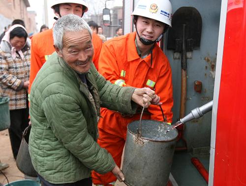2月18日,在伊川縣呂店鄉(xiāng)蘇溝村,消防隊員幫村民接水。 近期,河南省洛陽市伊川縣呂店鄉(xiāng)蘇溝村旱情嚴(yán)重,全村140戶村民面臨飲水困難。伊川縣公安消防大隊抽調(diào)人員、車輛為村民送水上門,幫助他們解決飲水問題。新華社發(fā)(李書寶 攝)