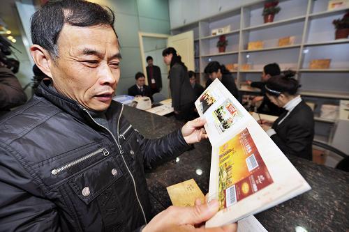 2月23日,一名市民欣賞剛剛購買的杭州市民消費(fèi)券珍藏冊(cè)。新華社發(fā)(李忠 攝)