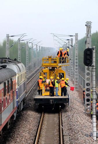 4月14日,中鐵電氣化局集團一公司的施工人員在作業(yè)車上操作。當(dāng)日,中鐵電氣化局集團一公司的施工人員在河北省境內(nèi)深州至邢家村區(qū)段成功架設(shè)起京九鐵路電氣化改造工程的第一條接觸網(wǎng)導(dǎo)線,標志著京九鐵路電氣化改造工程進入掛網(wǎng)架線階段。這項工程于2008年8月6日開工建設(shè),計劃2009年底竣工。京九鐵路實現(xiàn)電氣化改造后,列車運行最高時速將從160公里提高到200公里,運輸能力將提高近30%。新華社記者 王民 攝