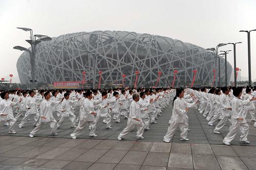 8月8日,愛好者們?cè)?#8220;鳥巢”前打太極拳。當(dāng)日,34000人在國家體育場“鳥巢”和國家游泳中心“水立方”之間的奧林匹克公園中心區(qū)景觀大道進(jìn)行太極拳表演。新華社記者 郭勇 攝