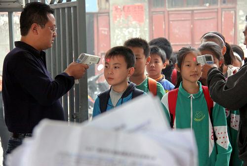 10月9日,河南省博愛縣實驗小學(xué)的教師用紅外線測溫儀對入校學(xué)生進(jìn)行晨檢。當(dāng)天是中小學(xué)、幼兒園在長假后正式上課的第一天,各地紛紛采取措施,嚴(yán)防甲流在校園和幼兒園蔓延。新華社發(fā)(程全 攝)
