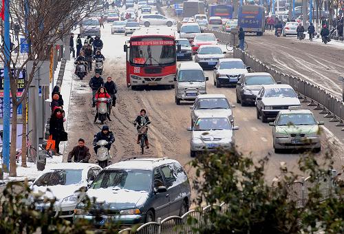 2月11日,機(jī)動車輛和和騎電動車的市民在濕滑的道路上緩慢前行。10日晚,鄭州市下了小到中雪。11日凌晨,城區(qū)最低氣溫降至零下4攝氏度。據(jù)氣象部門預(yù)測,今后兩日內(nèi),鄭州地區(qū)的天氣基本為多云或陰天,溫度會更低,但不會再有降雪。新華社記者 王頌 攝