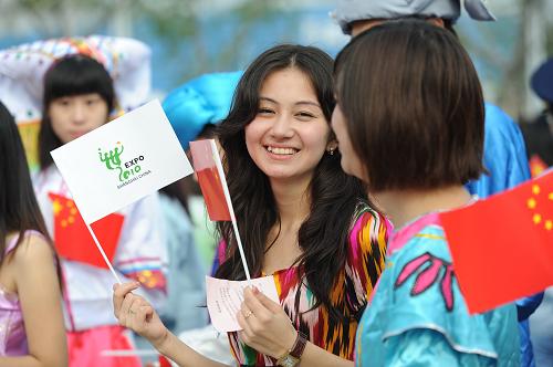 10月1日,維吾爾族少女迪麗努爾在升旗儀式上揮動國旗和世博旗幟。新華社記者 楊光 攝